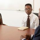 Chancellor Gary S. May with two students at a conference table