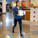 Student walks out of dining commons with takeout containers.