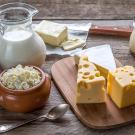 Pitcher of milk with cheese on board and containers of yogurt and cheese curds