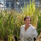 Pam Ronald stands in front of tall rice plants.