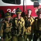 Four firefighters in front of a truck.