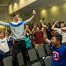 Student stands on chair in celebration.