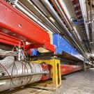 Large red and blue machines in a long tunnel curving to the right.