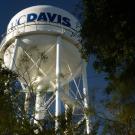 A water tower appears in a large reflection in water.