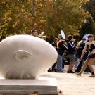 horizontal daytime photo of the Egghead 'Bookhead' with students walking in the background