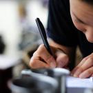 female bent over journal with pen writing