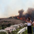 People watch a fire approaching homes