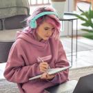 Young woman with pink hair and pink shirt, wearing headphones