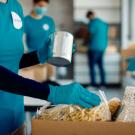 People, with no faces showing, fills boxes of groceries