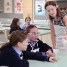 Students in school uniforms with lab equipment as teacher looks on