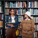 Two students model inside a library model the new Arneson Egghead Collection of apparel and accessories. 