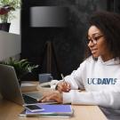 Woman with UC Davis shirt working at laptop computer