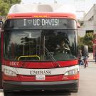 Front of modern Unitrans bus with vintage double-decker bus in background