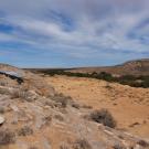 Arid landscape with shade cover over archaeological dig to left hand side. 