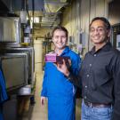 Scientists Erfan Rasouli in blue lab coat and Vinod Narayanan stand and smile in lab