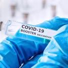 Syringe labeled "COVID-19 booster vaccination"