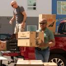 Chancellor Gary S. May lifts a box out of a truck.