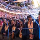 Confetti streamers fall down around graduates