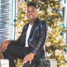 Black man in suit in front of gold background