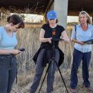 Three UC Davis scientists stand under highway overpass in field with sensor equioment. 