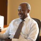 Chancellor Gary S. May, in shirt and tie, smiling, looking at phone.