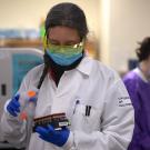 Woman holds tray of COVID-19 test samples.