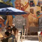 Students at tables in front of colorful mural