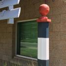 Black-and-white-striped racetrack distance marker with red ball on top