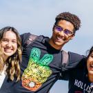 Young man with arms around two women, all three smiling in joyful group shot from report cover