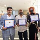 Three award winners stand with museum in background at a ceremony June 6, 2024