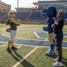 Luke Wood and Gary S. May stand across from each other on the football field, with Herky and Gunrock behind them.