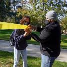 Man and woman tie yellow ribbon around tree.