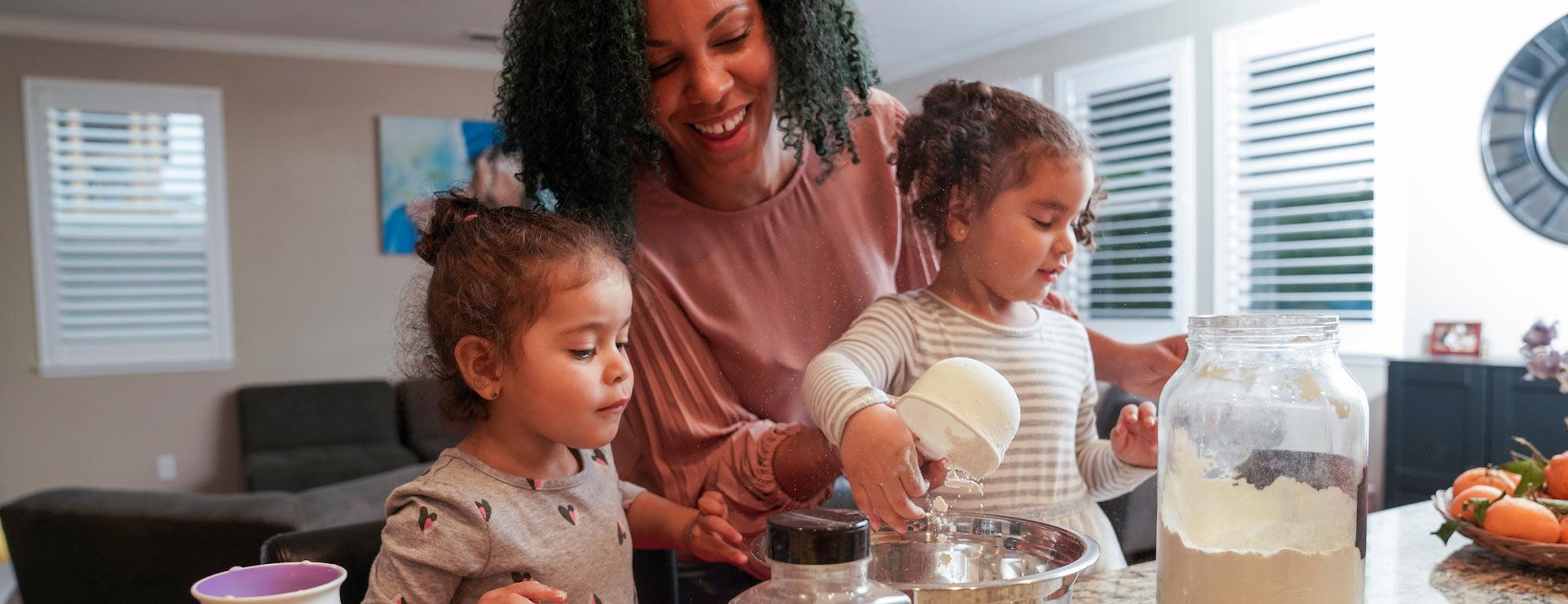 A mother cooks with her two young daughters