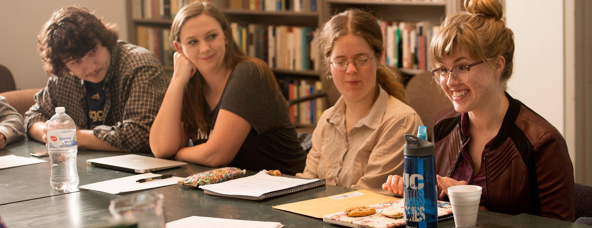 Students gather around a small table in a lively discussion with their professor