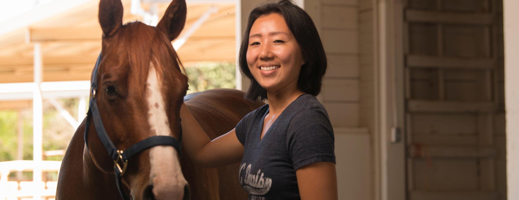 A student pets a horse