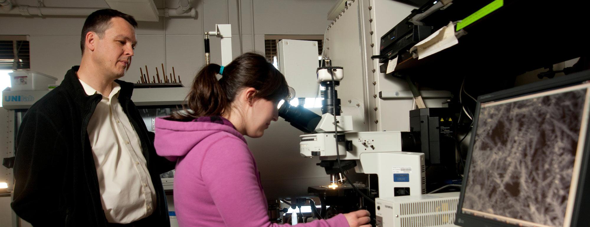 A student and her professor examine a slide specimen