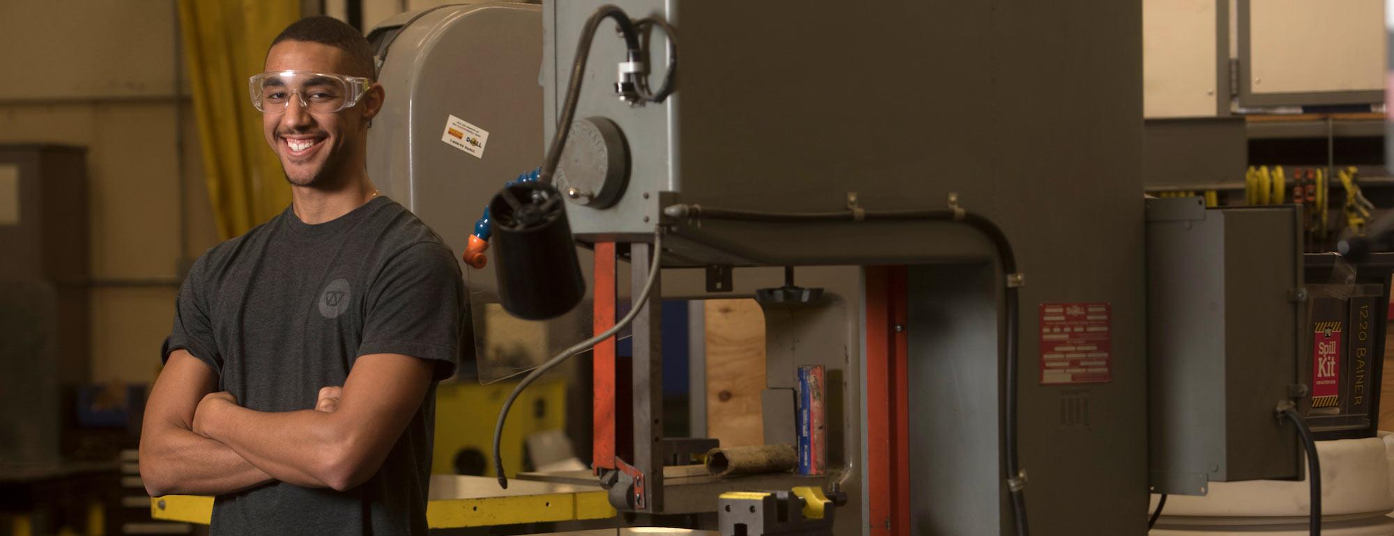 A male student poses with a machine press