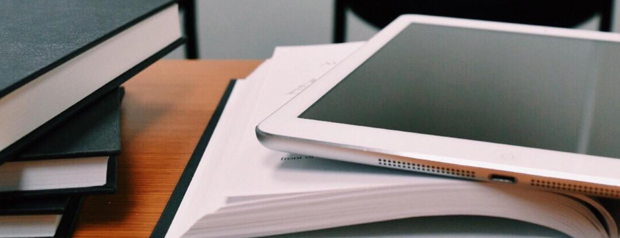 white ipad on top of open textbook