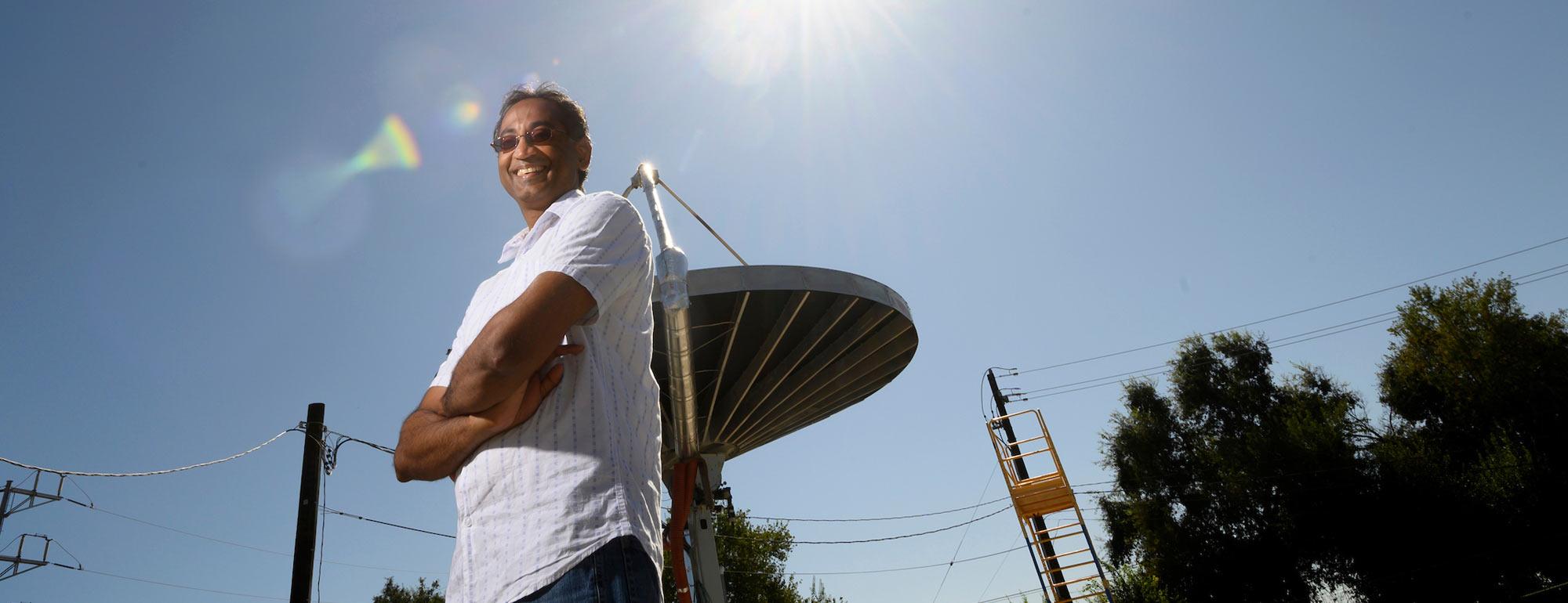 A professor posing in front of a solar heat amplifier.