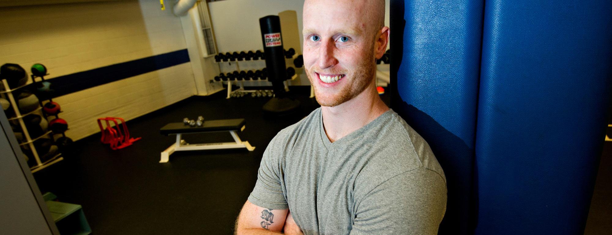 A male student poses next to exercise equipment