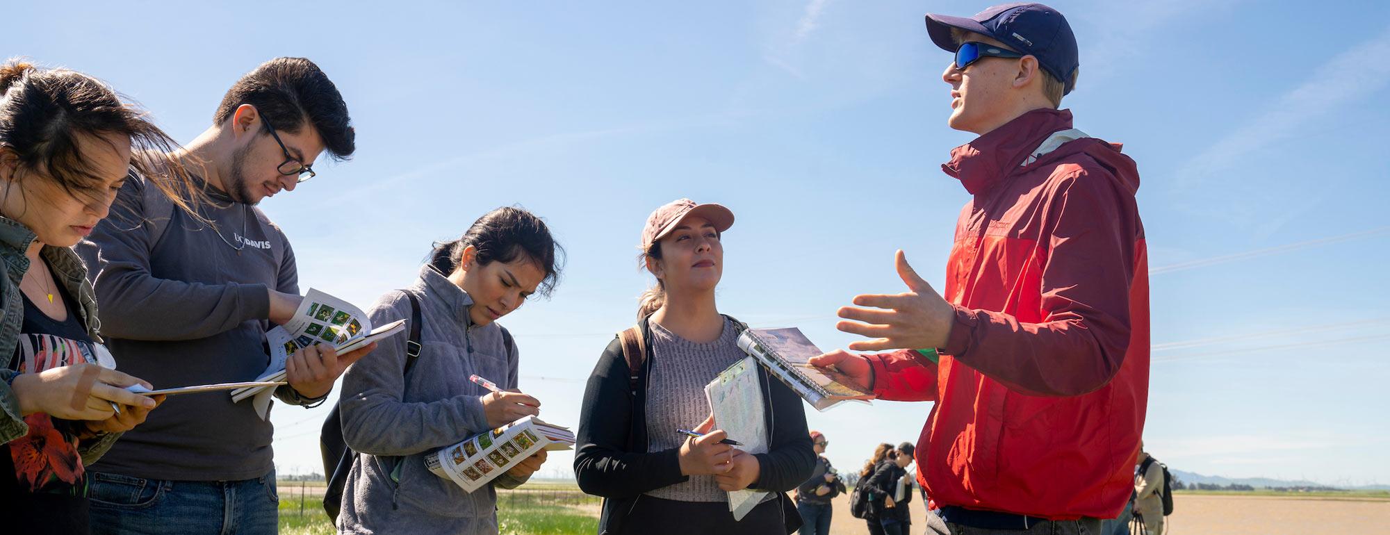 A student teacher lectures his class in the field