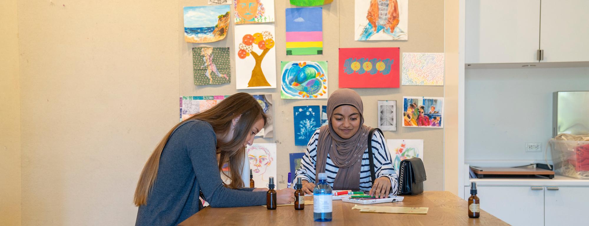 Two students work at a table surrounded by art at UC Davis. 