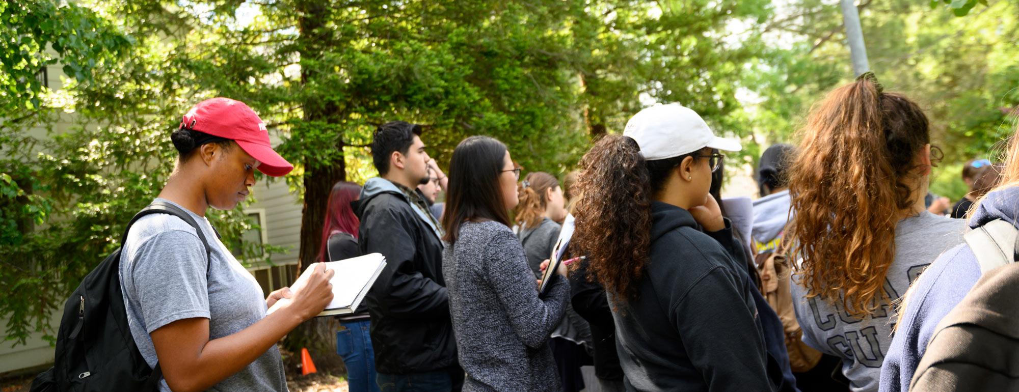 students in a landscape design class outside, one student taking notes