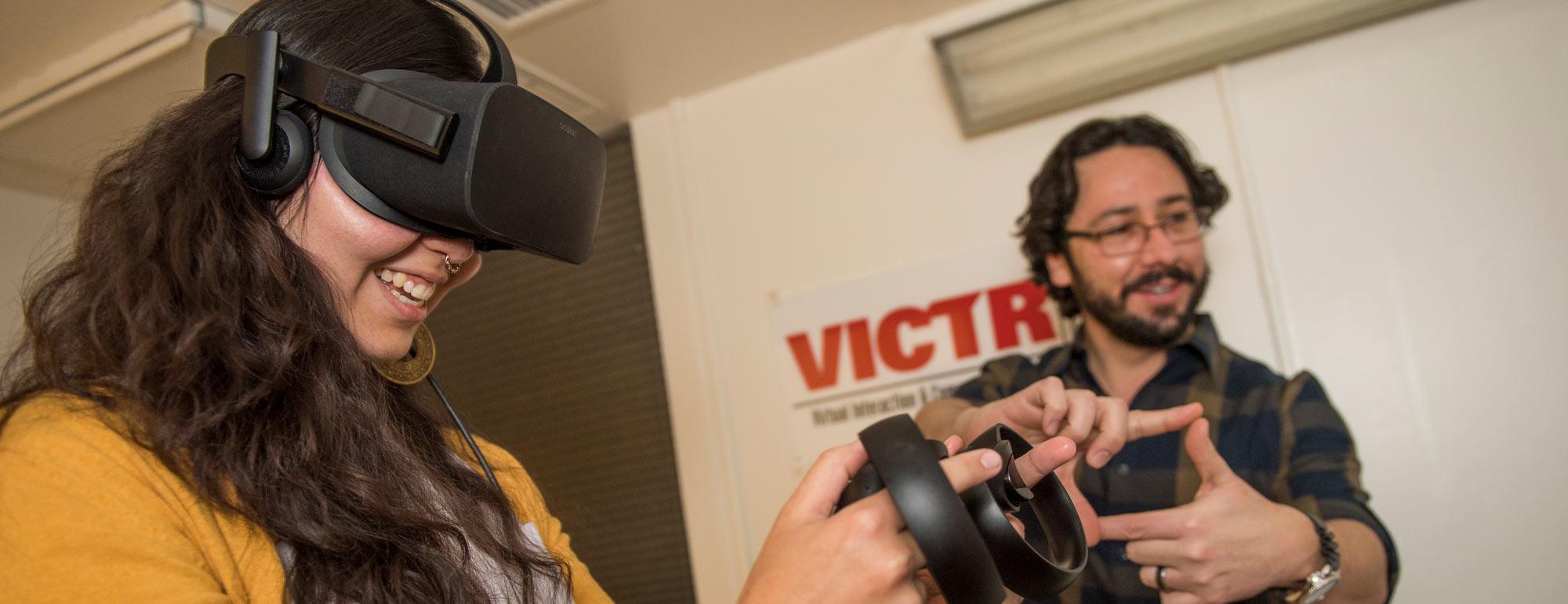 a student wearing VR goggles while a professor is guiding