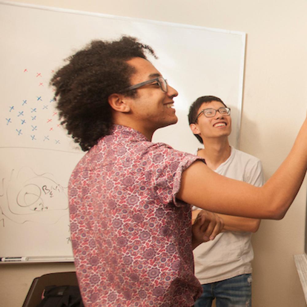 A student does equations at a blackboard.