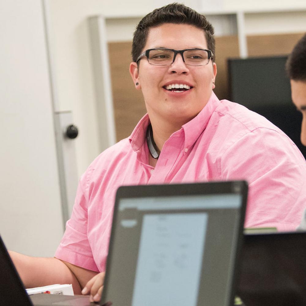 Three males students in a lively discussion over their laptops