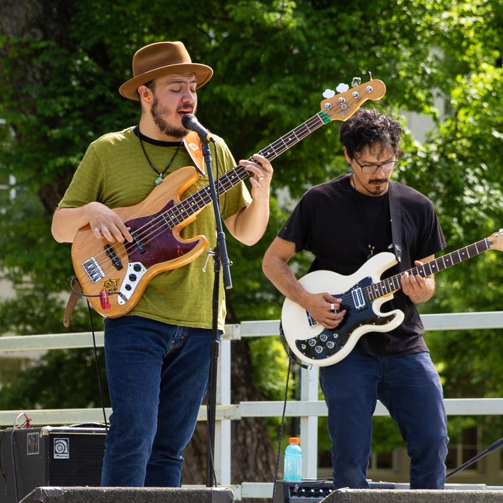 Two musicians playing guitar in a band on stage outside