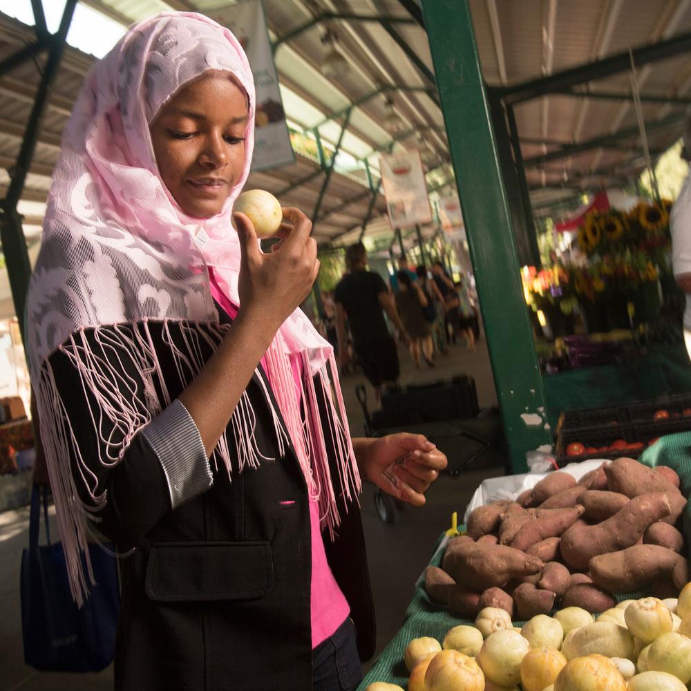 A female UC Davis student browses the fresh produce at the Davis Farmer's Market