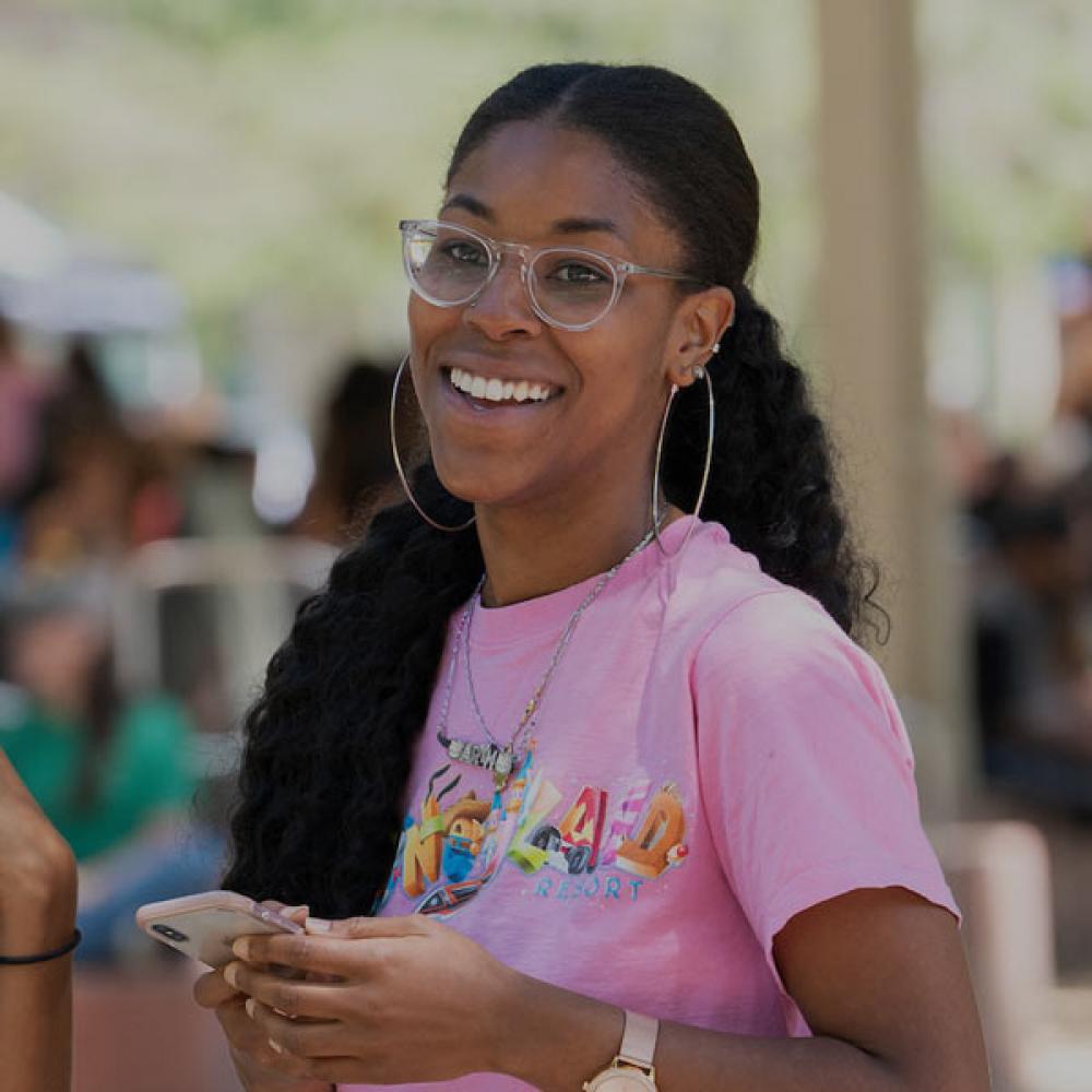 A smiling female student stands outside the UC Davis Memorial Union