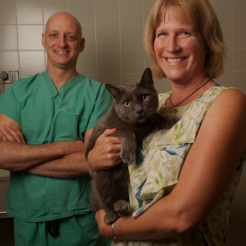 A woman and a veterinarian stand in an office holding a cat